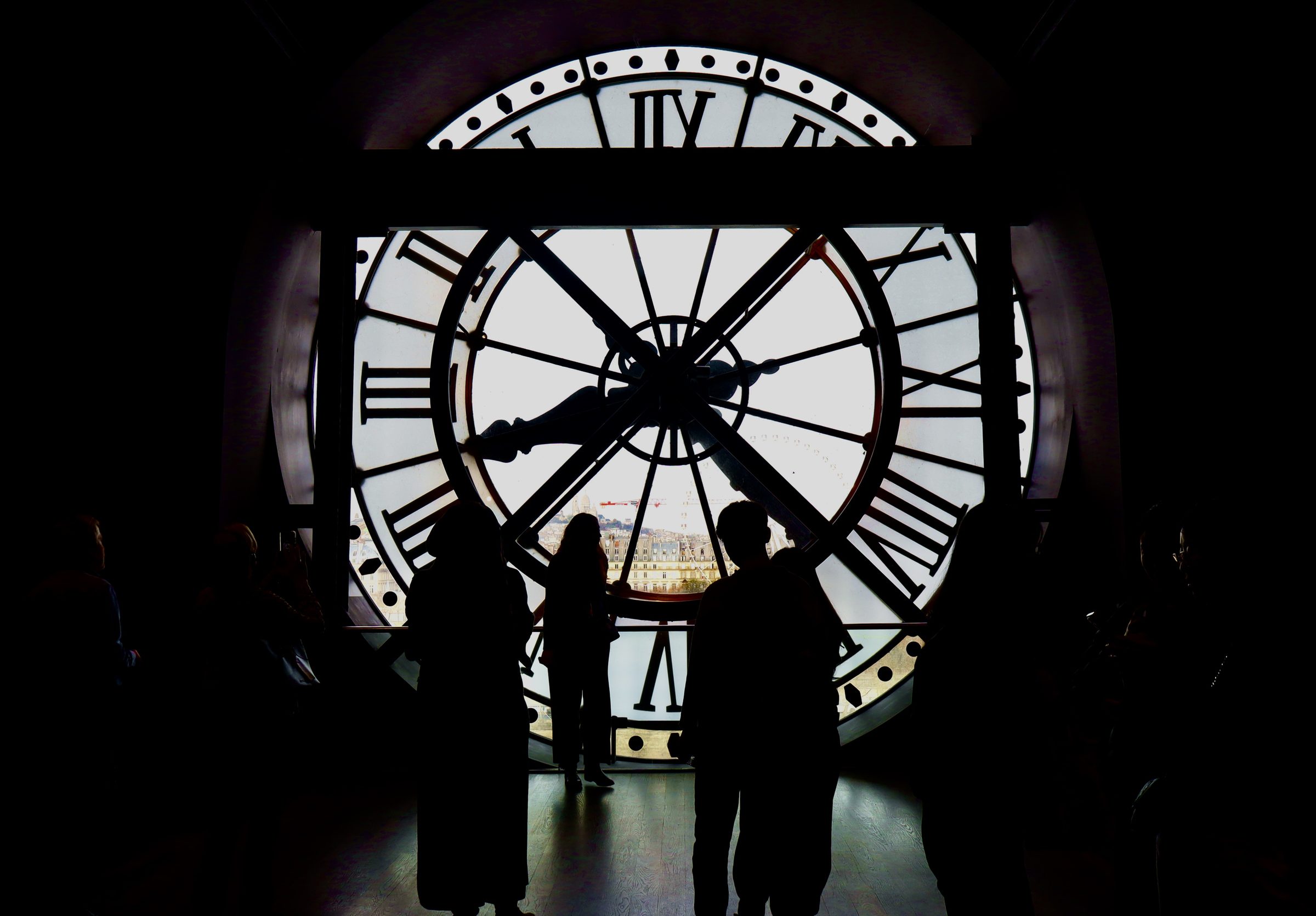 Silhouetted figures inside the great clock of the Musée d'Orsay, Paris, overlooking the city.